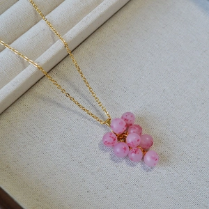 Détail du pendentif grappe en perles roses givrées sur collier chaîne dorée