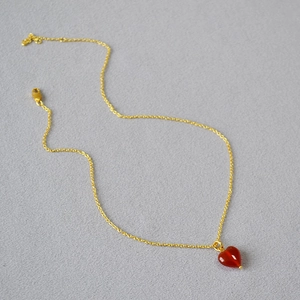 Macro shot of a red heart agate pendant on a delicate gold link chain necklace