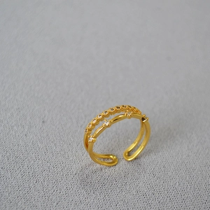 Minimalist double-layered gold ring with zircon stones on a grey textured surface