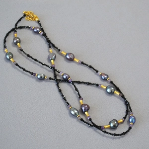 Baroque pearl and black spinel long necklace with gold accents on grey fabric