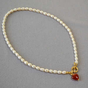 Detailed shot of pearl necklace with gold OT buckle and red agate heart pendant