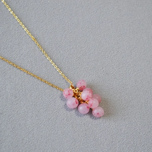 Détail du pendentif grappe aux perles rose pastel avec une fine chaîne dorée élégante