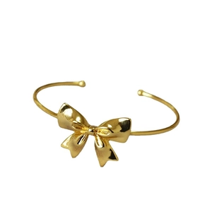 Minimalist gold-plated brass bow knot open cuff bracelet on white background
