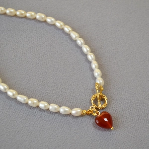 Macro shot of pearl necklace featuring a red heart pendant and vintage gold OT toggle clasp