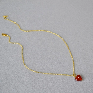 Minimalist gold necklace featuring a polished red heart agate pendant on a fine chain
