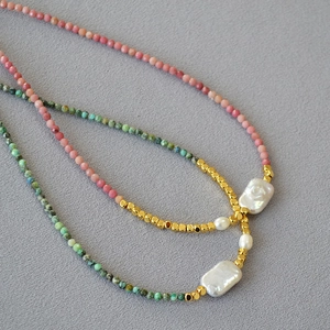 Detail of baroque pearl necklace with pink and turquoise beads on grey fabric