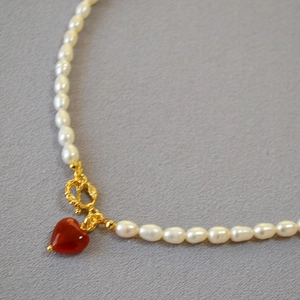 Detail of pearl necklace featuring gold OT clasp and red heart agate gemstone pendant
