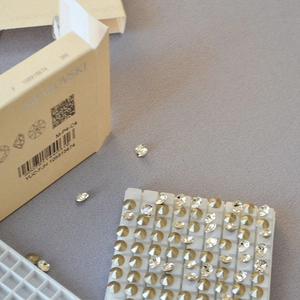 Close-up of sparkling crystal stud earrings in a white tray with yellow packaging