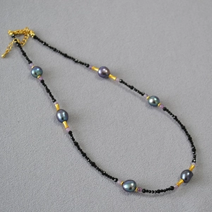 Detailed view of handmade necklace with black faceted beads and dark baroque pearls
