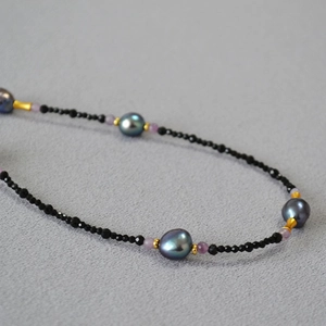 Macro shot of long necklace with black spinel beads and baroque peacock pearls