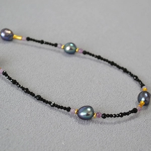 Detail of baroque pearls with purple luster and black faceted spinel beads on long necklace