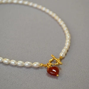 Macro detail of pearl necklace with gold OT toggle clasp and red agate heart pendant