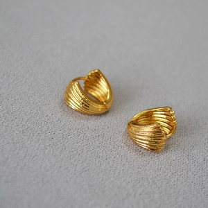 Detailed macro shot of vintage shell-shaped brass earrings with gold plating and ribbed texture