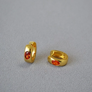Minimalist gold brass hoop earrings with oval orange zircon stones on gray background