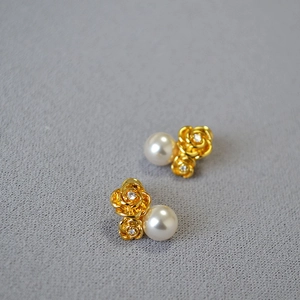 Macro detail of elegant pearl earrings with golden rose petals and zircon accents