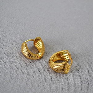Macro view of gold-plated shell-shaped earrings with textured radial grooves