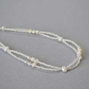 Close-up of double-layer necklace with Baroque pearls and white seed beads on fabric