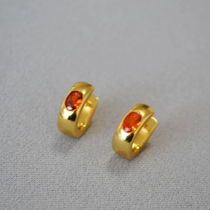 Detailed view of gold-plated brass hoop earrings with oval orange zircon gemstones