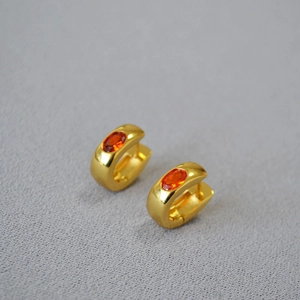 Detailed close-up of gold-plated hoop earrings featuring oval orange-red gemstones