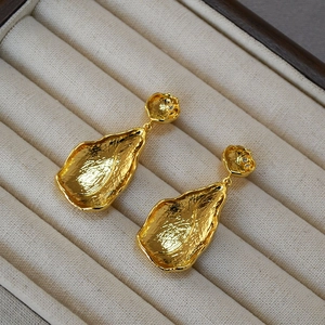 Detailed macro view of hammered golden leaf earrings with small inset rhinestones