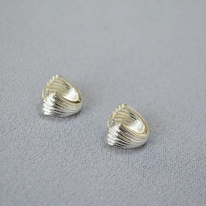 Macro shot of silver shell-shaped huggie earrings with textured vertical ridges