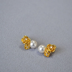 Macro view of gold rose flower earrings with white pearls and sparkling cubic zirconia