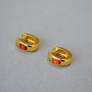 Detailed shot of gold-plated U-shaped earrings featuring faceted oval orange gemstones