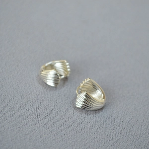 Detailed view of silver hoop earrings featuring vertical shell texture and fan-shaped design