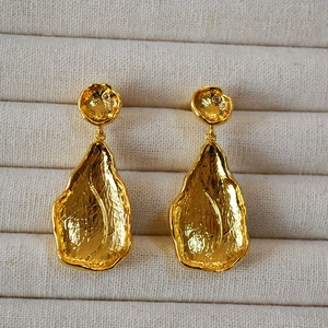 Detail of gold leaf drop earrings with hammered texture and white zircon stone inlay