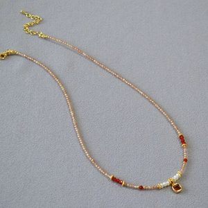 Detail of beaded necklace with champagne zircons, pearls, and red gemstone pendant