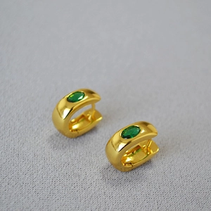 Detail of C-shaped gold-plated hoop earrings featuring oval green zircon stones