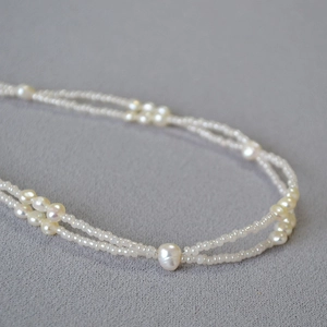 Macro shot of double-layer Baroque pearl necklace on a textured grey fabric background