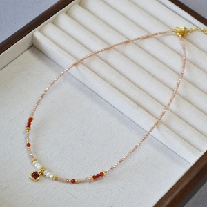 Detailed shot of beaded necklace with freshwater pearls and square gold pendant