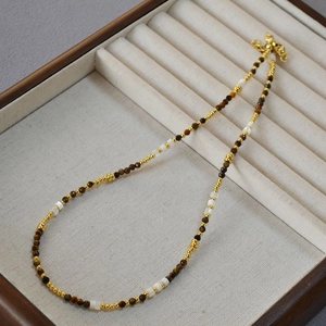 Dettaglio della collana con occhio di tigre e conchiglia su vassoio per gioielli