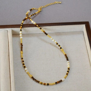 Collana vintage di perline con pietre occhio di tigre e madreperla su vassoio di legno
