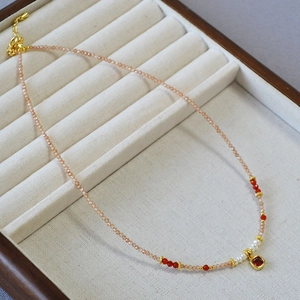 Detailed shot of champagne zircon beads with freshwater pearls and a red gemstone pendant