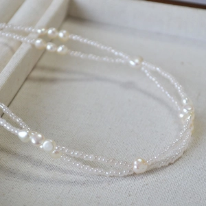 Macro detail of double-layered baroque pearl necklace with delicate seed beads