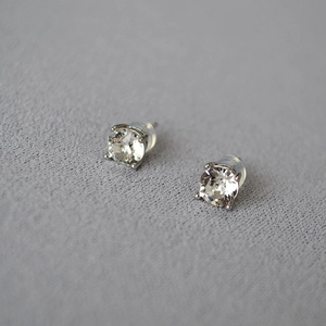 Detailed macro view of sparkling silver stud earrings with classic four-prong crystal setting