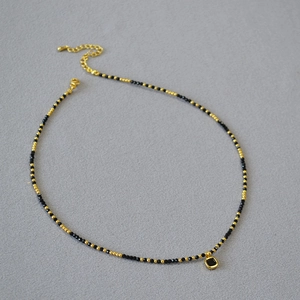 Détail du collier de perles en spinelle noire avec perles dorées et pendentif carré