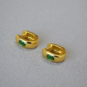 Macro view of gold-plated U-shaped earrings with oval green gemstones and clasp detail