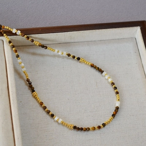 Dettaglio della collana di perline con occhio di tigre e conchiglia su vassoio