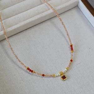Detail of beaded necklace with freshwater pearls and red stone pendant in jewelry box