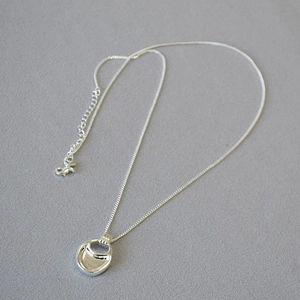 Macro detail of polished S925 silver round pendant with adjustable cross chain lobster clasp