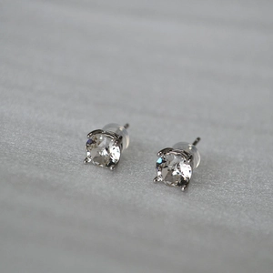 Macro detail of classic four-prong sparkling crystal stud earrings with silver pins