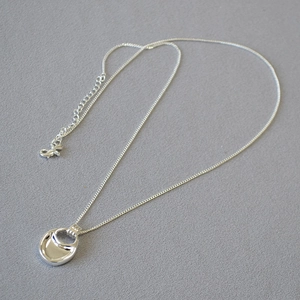 Macro shot of silver saddle-shaped pendant with polished finish and adjustable O-chain