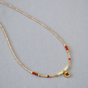 Detail of freshwater pearls and zircon necklace with a gold-rimmed red gemstone pendant