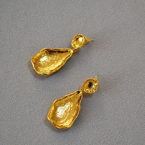 Close-up of gold-plated leaf earrings with hammer texture and small zircon details