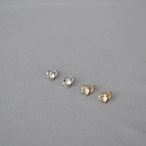 Detail view of round claw-set crystal stud earrings in silver and gold finishes