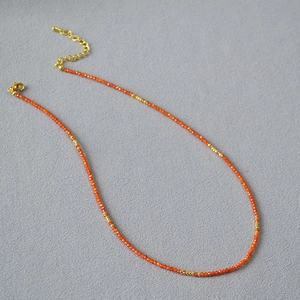 Detailed macro view of orange beaded necklace with gold metal spacers and lobster clasp