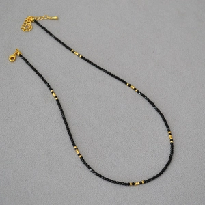 Collier de perles à plusieurs rangs avec spinelle noire et accents dorés sur tissu gris